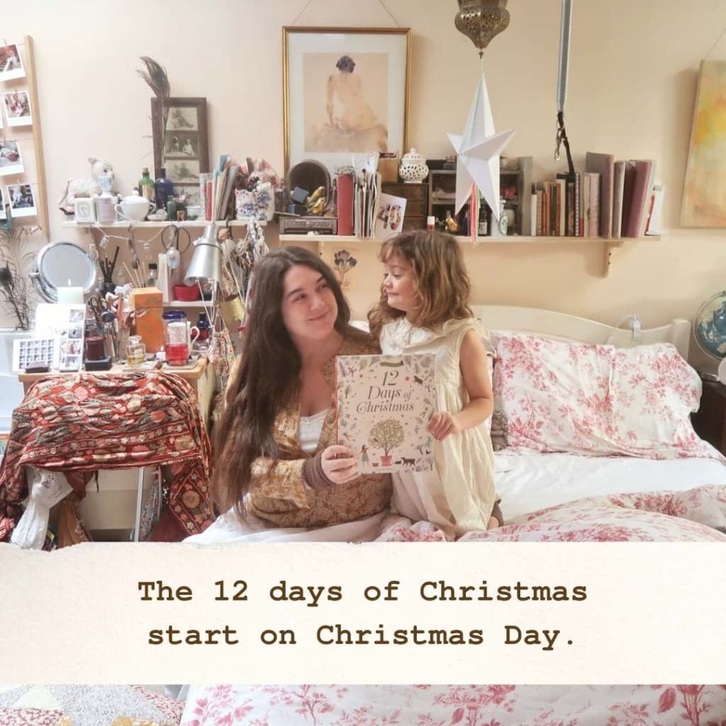 I'm in bed with Mainie next to me, she's holding a picture book - The Twelve Days of Christmas. Our text reads ''the 12 days of Christmas start on Christmas Day'.